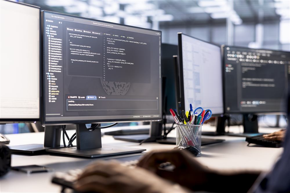 Manos escribiendo en teclado frente a monitor